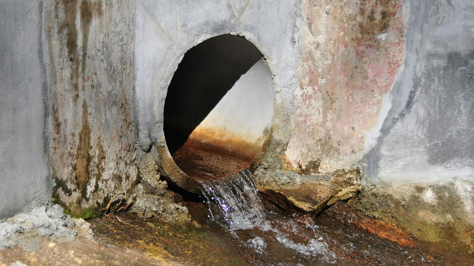 Salida de una tubería de desagüe vertiendo agua en un canal de hormigón